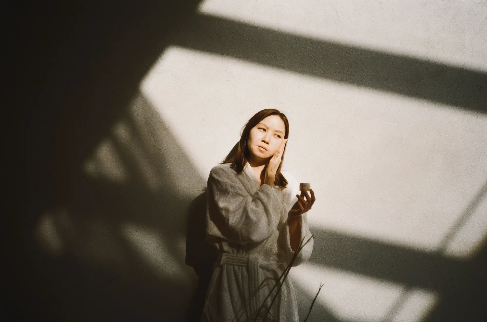 A woman pressing serum into her skin in warm morning light